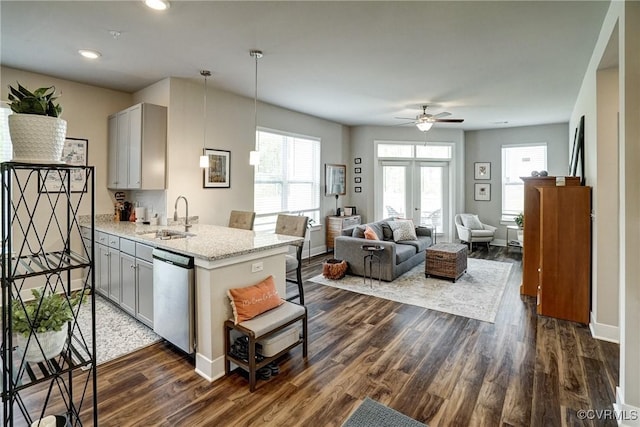 kitchen featuring a ceiling fan, dishwasher, a sink, baseboards, and dark wood-style floors