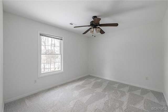 spare room featuring a ceiling fan, baseboards, visible vents, and light carpet