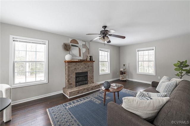 living room with a fireplace, a ceiling fan, baseboards, and dark wood-type flooring