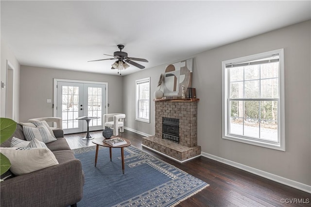 living area featuring french doors, baseboards, ceiling fan, and a fireplace