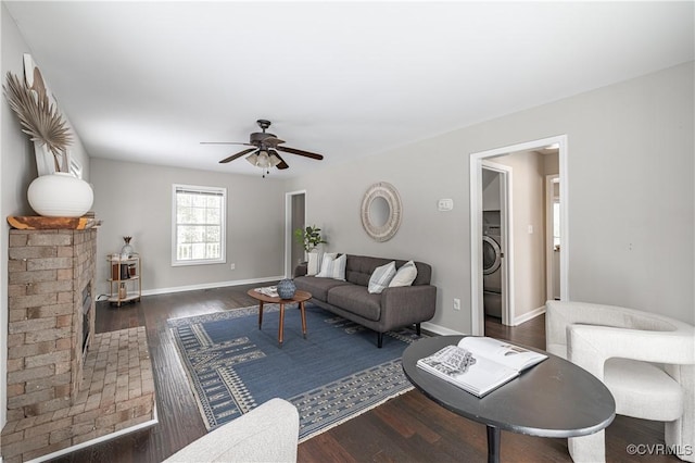 living room featuring washer / dryer, baseboards, ceiling fan, and wood finished floors