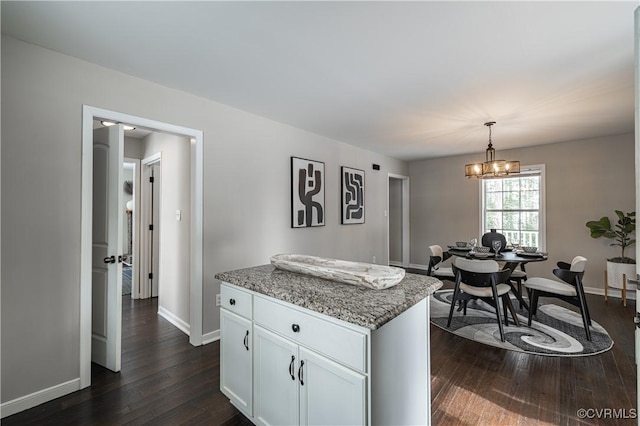 kitchen featuring pendant lighting, dark wood-style flooring, baseboards, white cabinets, and light stone counters