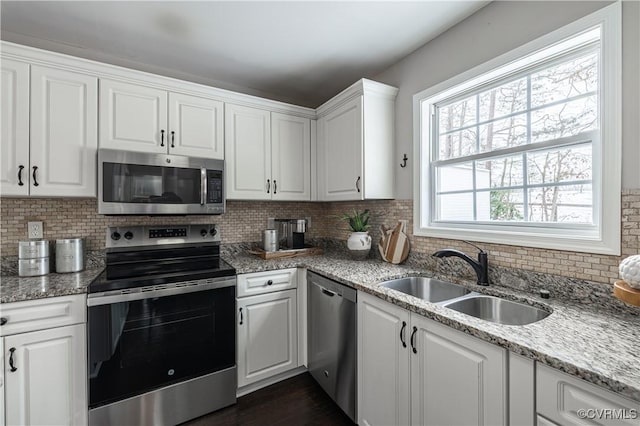 kitchen featuring white cabinets, appliances with stainless steel finishes, decorative backsplash, and a sink