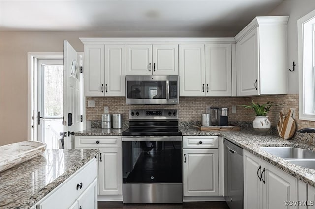 kitchen featuring a sink, white cabinetry, tasteful backsplash, and stainless steel appliances