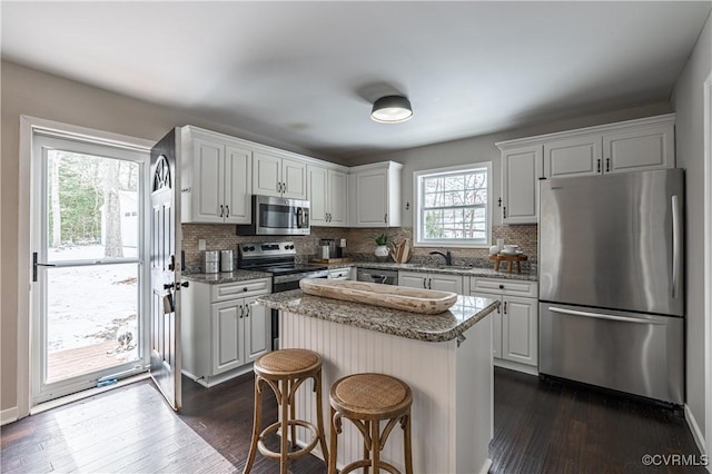 kitchen featuring a sink, dark wood-style flooring, decorative backsplash, and stainless steel appliances