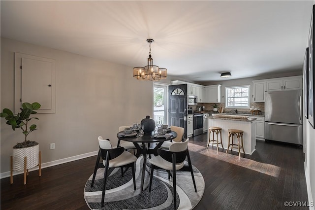 dining area featuring baseboards, dark wood-style flooring, and a notable chandelier