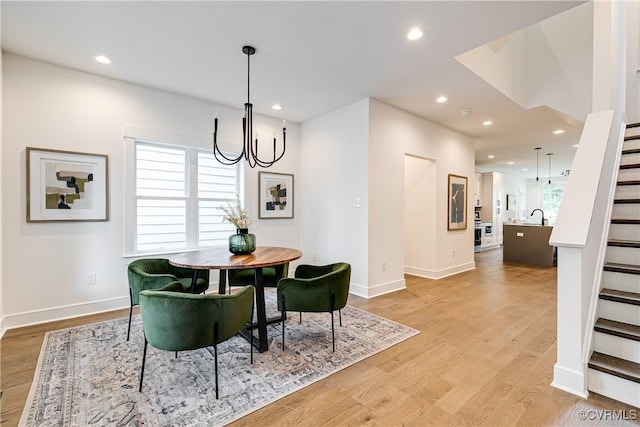 dining area with an inviting chandelier, recessed lighting, light wood-style floors, and stairway