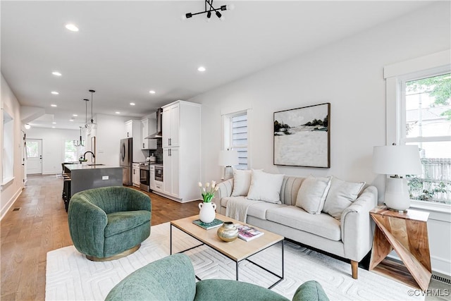 living room featuring baseboards, recessed lighting, and light wood-style flooring