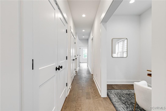 hallway featuring recessed lighting, baseboards, and light wood-style flooring