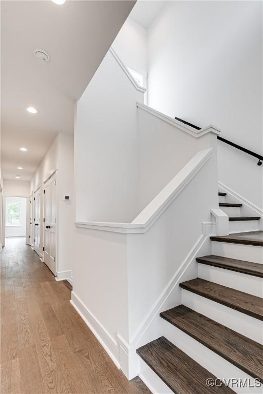 staircase with recessed lighting, baseboards, and wood finished floors
