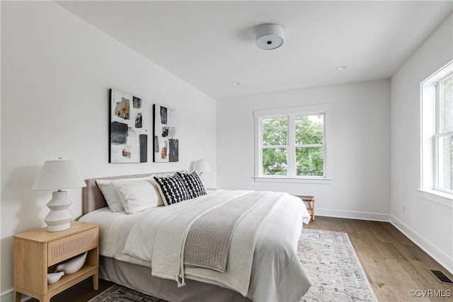 bedroom featuring visible vents, baseboards, and wood finished floors
