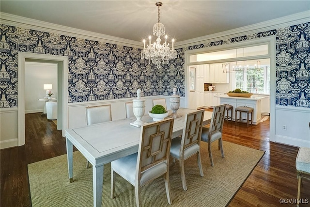 dining area featuring dark wood-style flooring, wallpapered walls, a chandelier, and ornamental molding