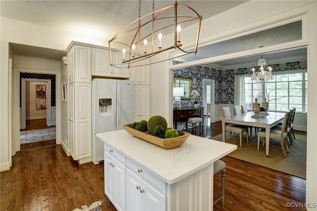 kitchen featuring dark wood-style flooring, wallpapered walls, a notable chandelier, and white fridge with ice dispenser