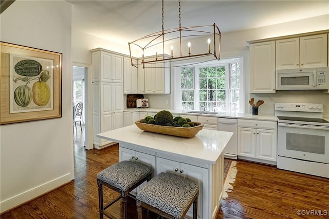 kitchen with dark wood-style flooring, a sink, light countertops, an inviting chandelier, and white appliances