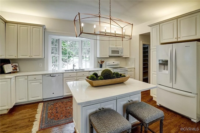 kitchen featuring a sink, white appliances, light countertops, a center island, and dark wood-style floors