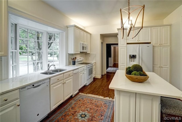 kitchen featuring dark wood finished floors, a sink, light countertops, a notable chandelier, and white appliances
