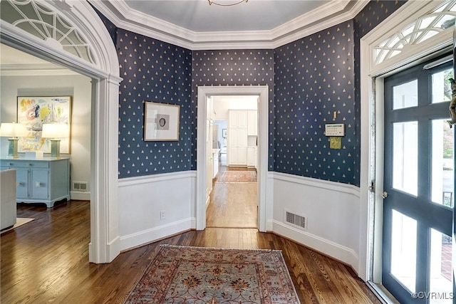 entryway featuring visible vents, wood finished floors, a wainscoted wall, ornamental molding, and wallpapered walls