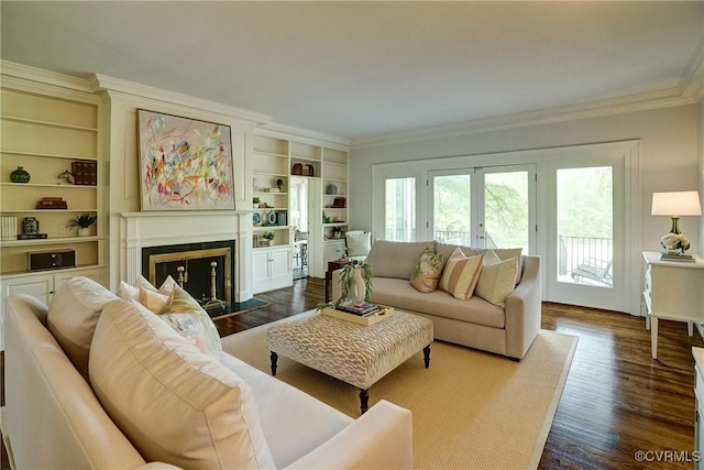 living room with crown molding, built in features, dark wood finished floors, and a fireplace with flush hearth
