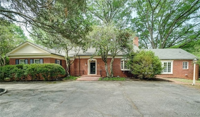 single story home featuring a chimney and brick siding