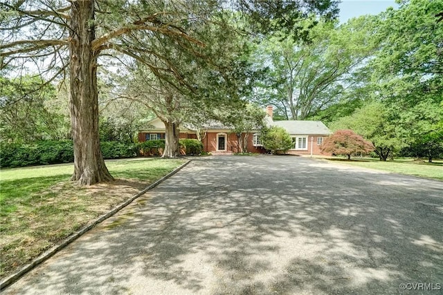 view of front of home with a front yard, driveway, and a chimney