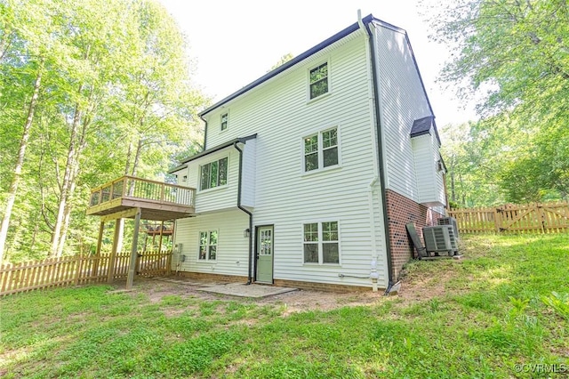 back of house featuring a lawn, a fenced backyard, a wooden deck, and cooling unit