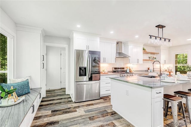 kitchen featuring wall chimney range hood, range, a sink, stainless steel fridge with ice dispenser, and light wood-style floors
