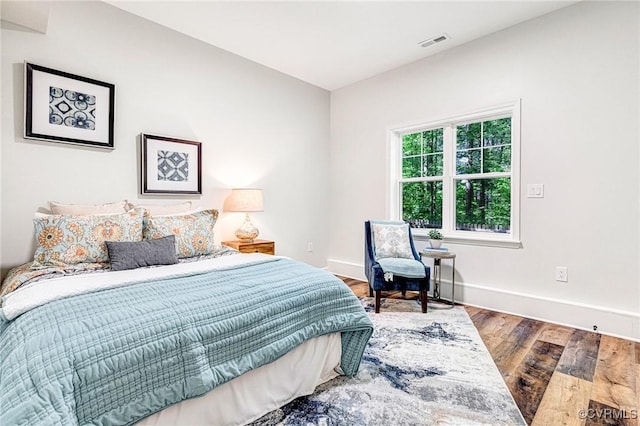 bedroom featuring visible vents, baseboards, and wood finished floors