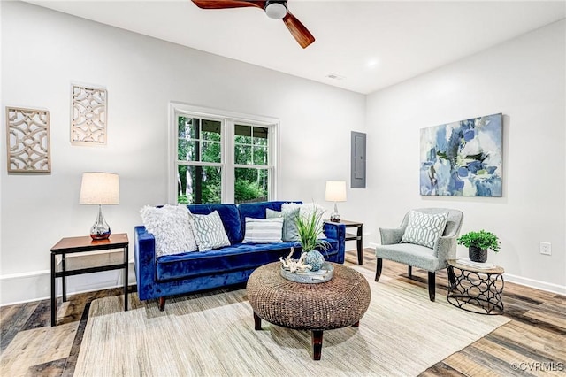 living room with ceiling fan, baseboards, wood finished floors, visible vents, and electric panel