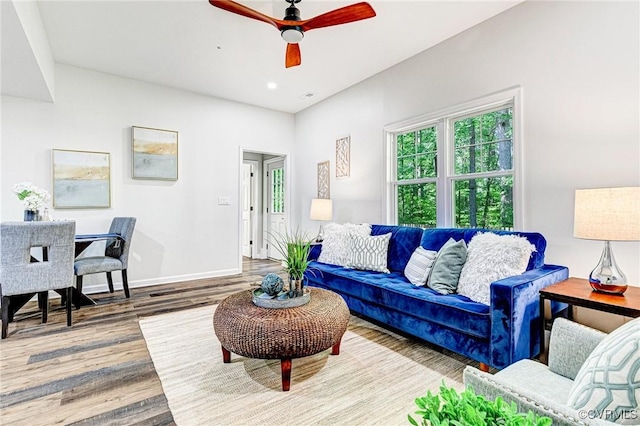 living area featuring a ceiling fan, baseboards, and wood finished floors
