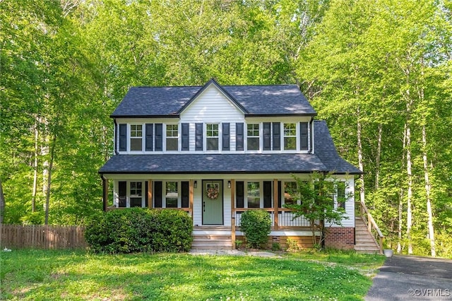 view of front facade featuring a shingled roof, a front lawn, fence, and covered porch