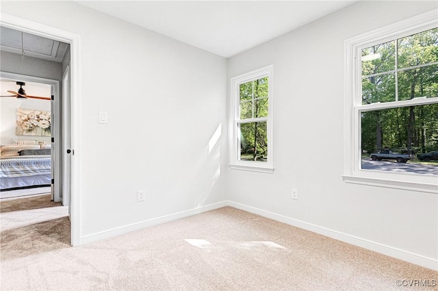 carpeted spare room featuring baseboards and attic access