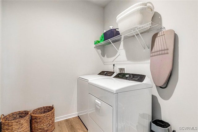clothes washing area featuring washer and dryer, laundry area, baseboards, and light wood-type flooring