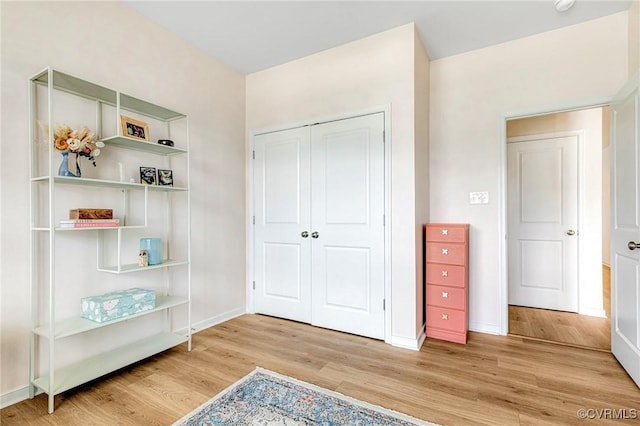 unfurnished bedroom with baseboards, wood finished floors, and a closet