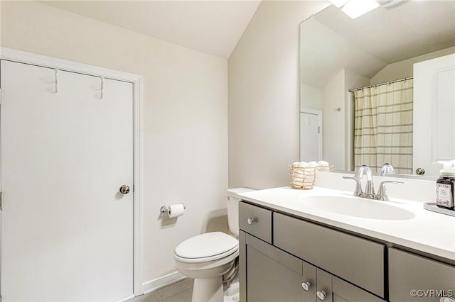 bathroom featuring tile patterned flooring, vanity, toilet, baseboards, and vaulted ceiling