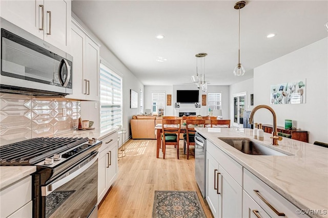 kitchen featuring light wood-style floors, recessed lighting, a sink, hanging light fixtures, and stainless steel appliances