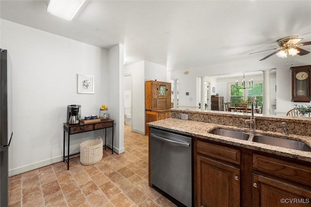 kitchen with stone finish floor, ceiling fan, dishwasher, a sink, and baseboards