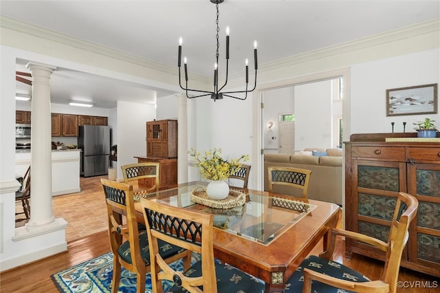 dining space featuring ornate columns, a chandelier, ornamental molding, and light wood-type flooring