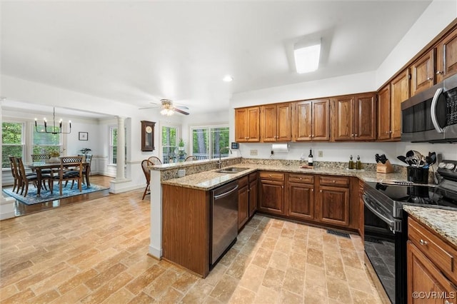 kitchen featuring appliances with stainless steel finishes, a sink, ceiling fan with notable chandelier, a peninsula, and ornate columns