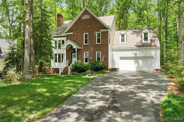 colonial inspired home featuring a front lawn, roof with shingles, a chimney, an attached garage, and driveway