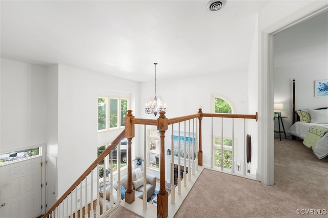 stairs featuring an inviting chandelier, carpet flooring, and visible vents
