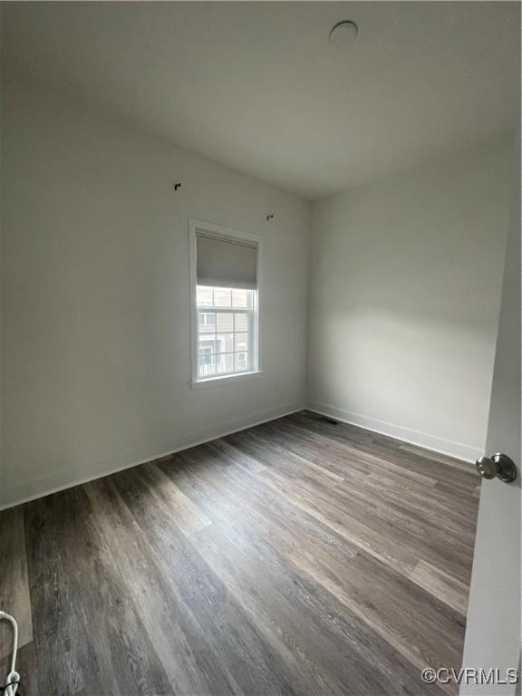 empty room featuring baseboards and dark wood-style flooring