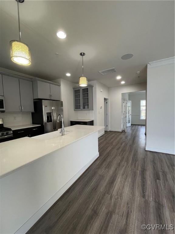 kitchen featuring visible vents, light countertops, a sink, dark wood-style floors, and stainless steel appliances