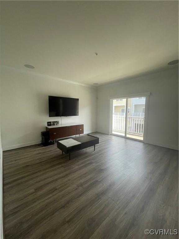 living area with baseboards, ornamental molding, and dark wood-type flooring