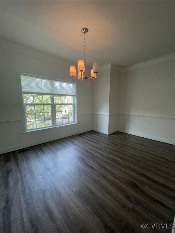 empty room featuring crown molding, dark wood finished floors, baseboards, and a notable chandelier