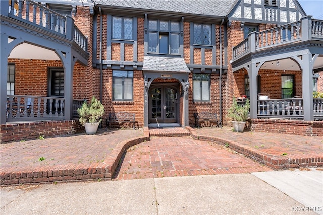 exterior space with a balcony, roof with shingles, and brick siding