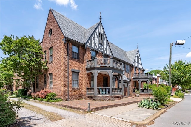 view of front facade with brick siding and a balcony