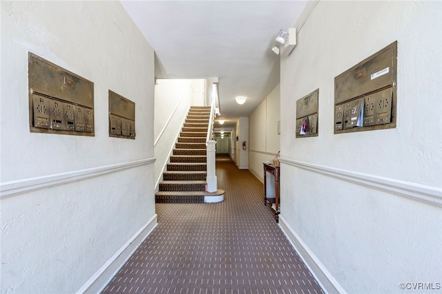 hallway with stairway, baseboards, and carpet