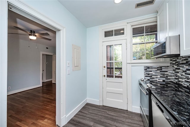 kitchen featuring white cabinets, appliances with stainless steel finishes, dark wood-style floors, and tasteful backsplash