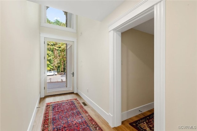 doorway featuring baseboards, light wood finished floors, and visible vents
