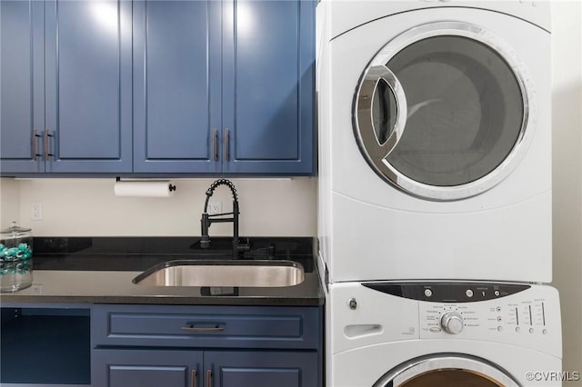 laundry area featuring cabinet space, stacked washing maching and dryer, and a sink